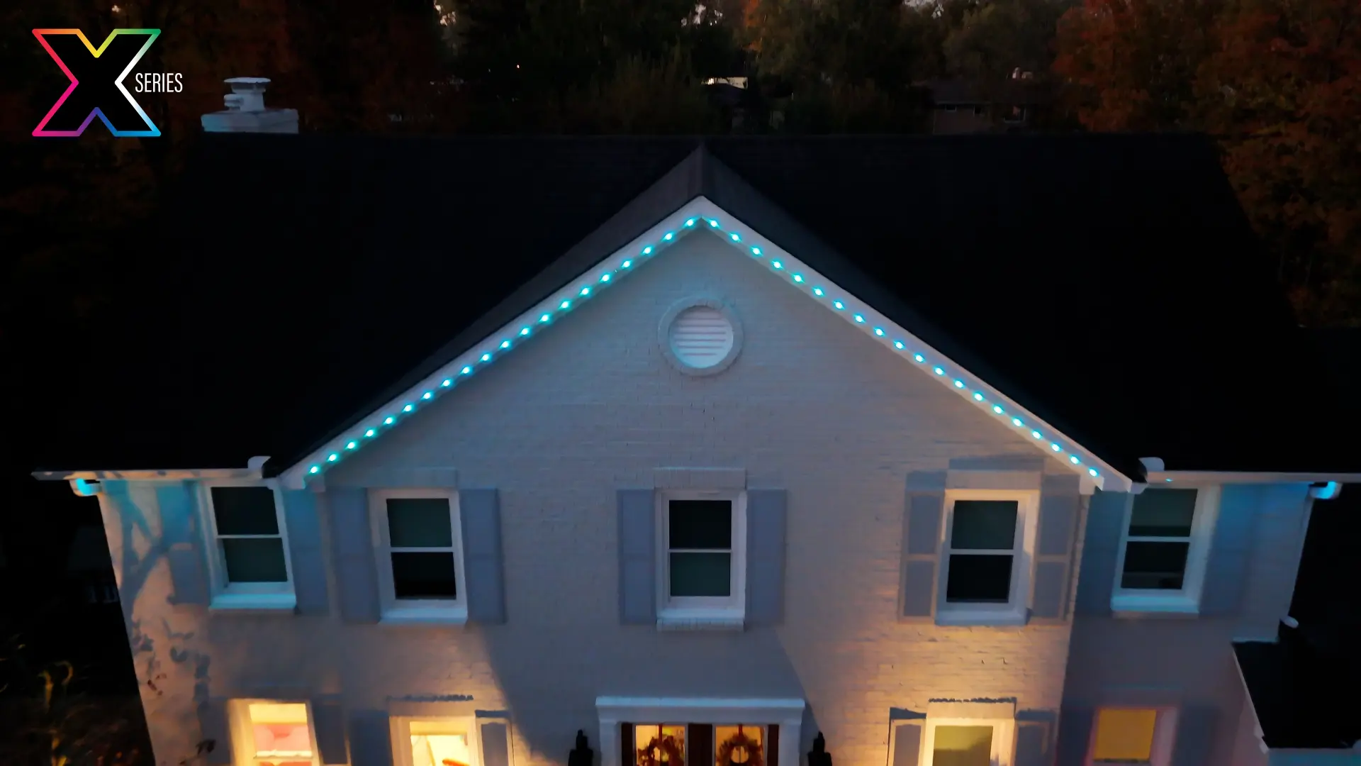 Brick home gable outlined in teal permanent roofline lighting